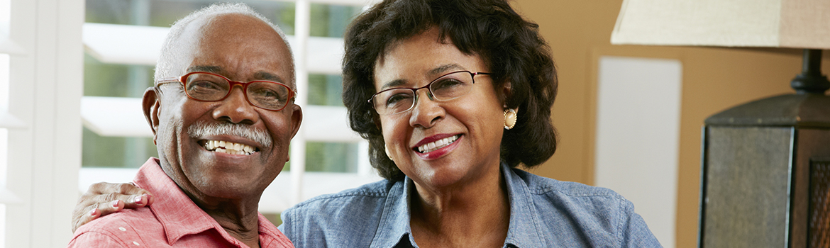 Senior couple on their living room sofa smiling at the viewer